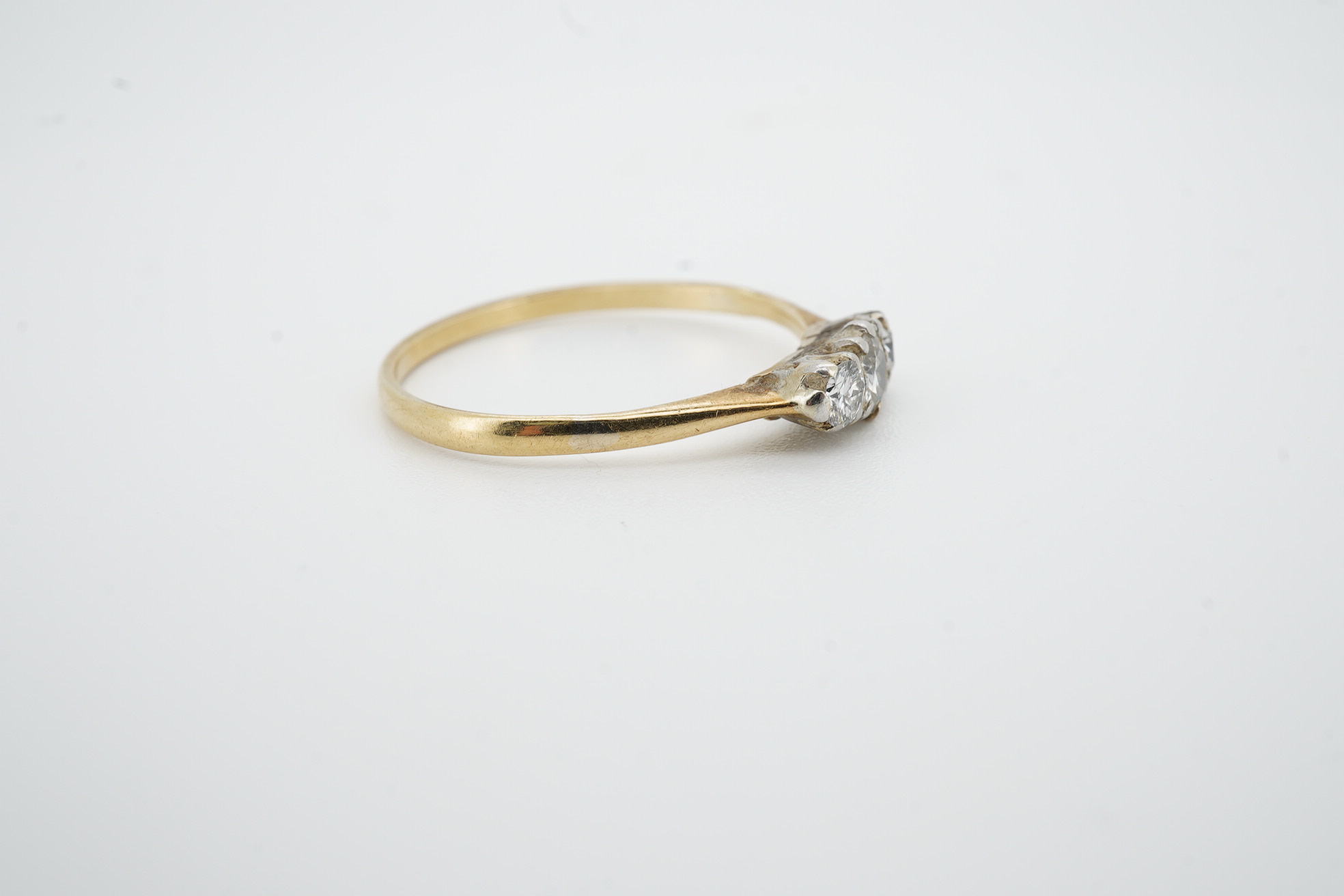 A yellow metal and three stone diamond set ring, size R/S, gross weight 2 grams. Condition - poor to fair